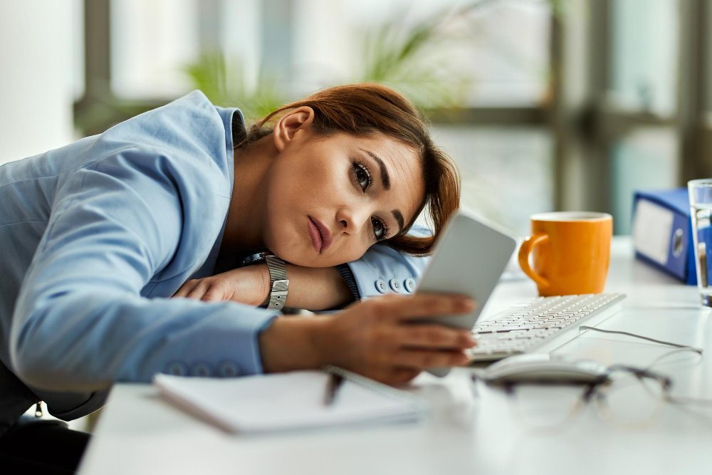 mujer-negocios-pensativa-usando-telefono-movil-mientras-relaja-oficina